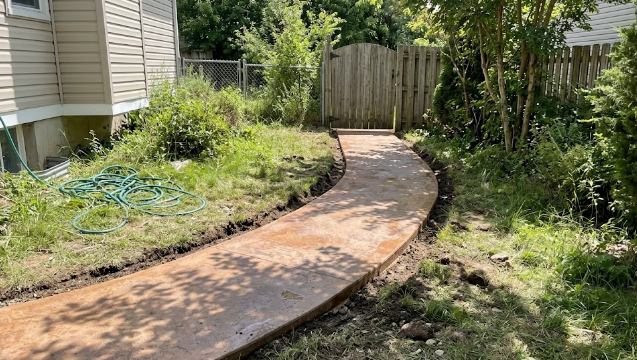 Decorative stained concrete walkway leading through a green residential garden