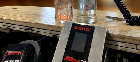 A berg phone is sitting on a counter next to two glasses of water.