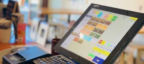 A computer monitor is sitting on top of a cash register.