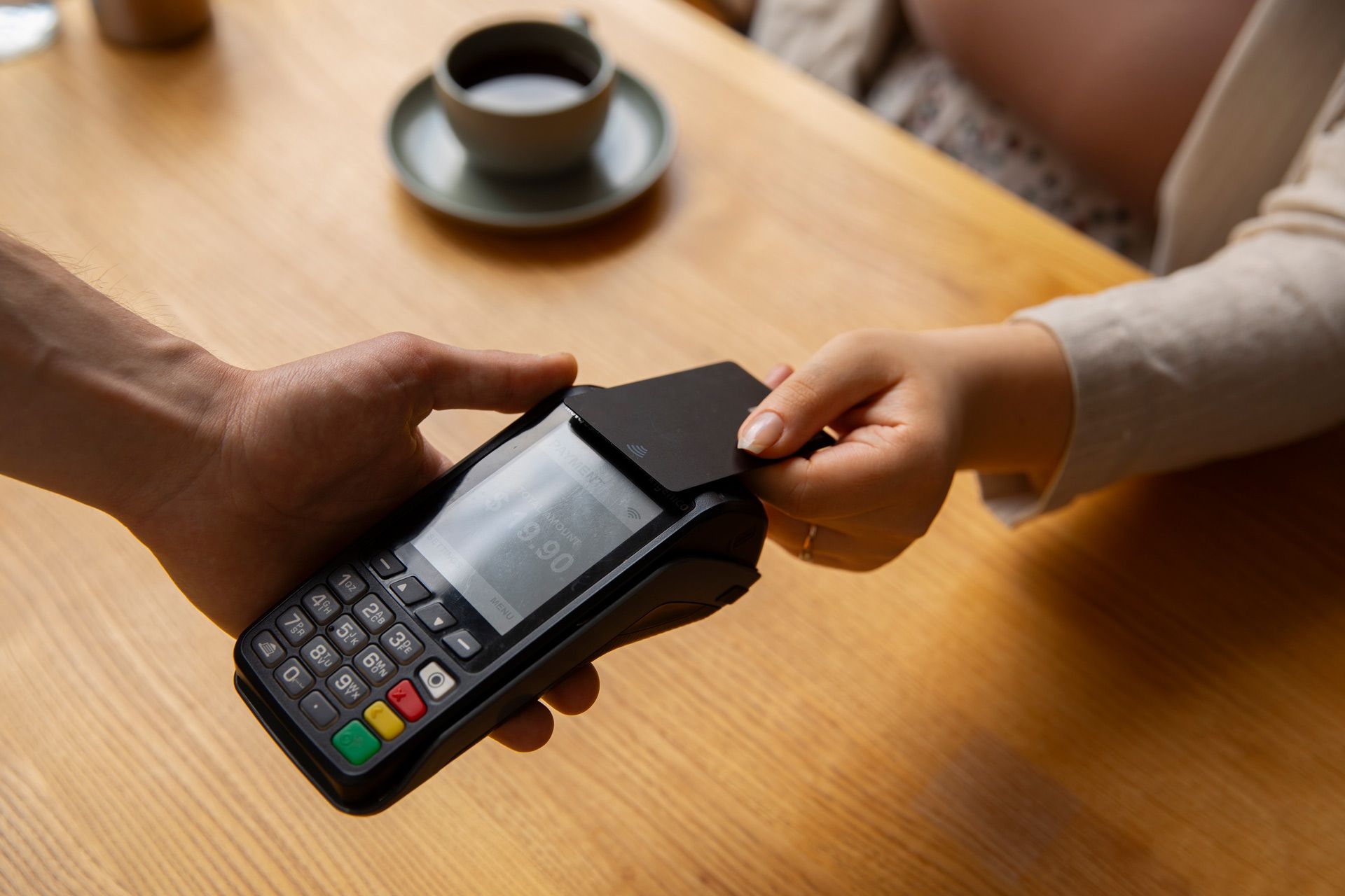 A woman is paying with a credit card on a credit card machine.