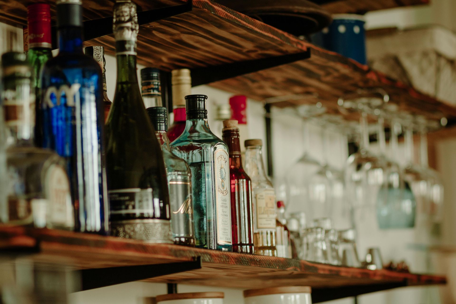 A shelf filled with bottles of alcohol and wine glasses.
