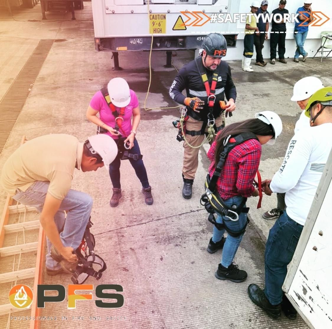 Personas con arneses de seguridad, ajustando equipos al aire libre cerca de un vehículo.