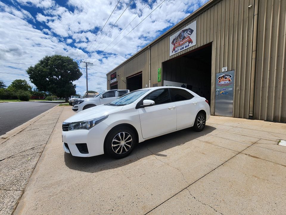A white car is parked in front of a building — Ace Tinting in Mareeba, QLD