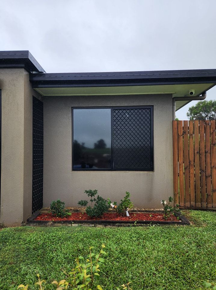 A small house with a large window and a wooden fence — Ace Tinting in Mareeba, QLD