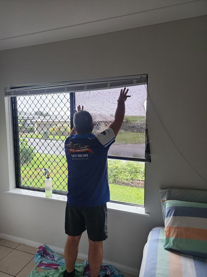 A man is standing in front of a window in a bedroom — Ace Tinting in Mareeba, QLD