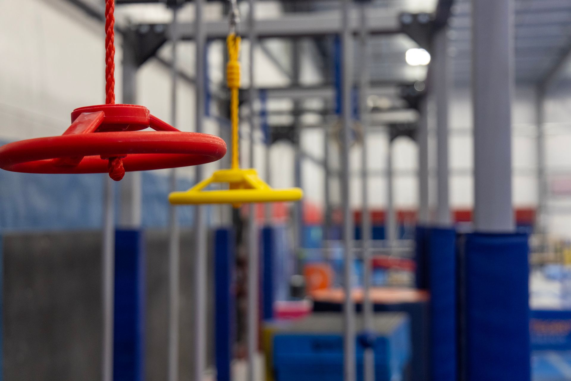 Red and yellow industrial hanging pull cords in a factory aisle with blue equipment in the background