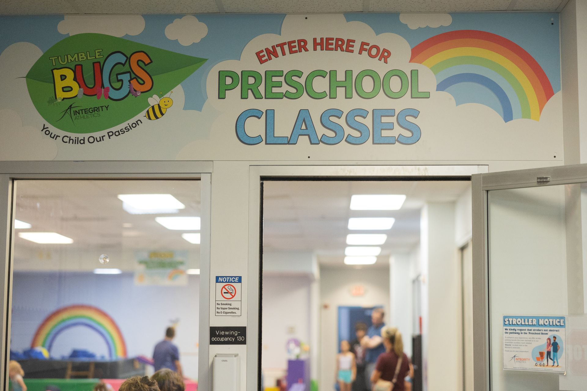 Entrance sign for preschool classes with rainbow decorations and a playroom visible inside