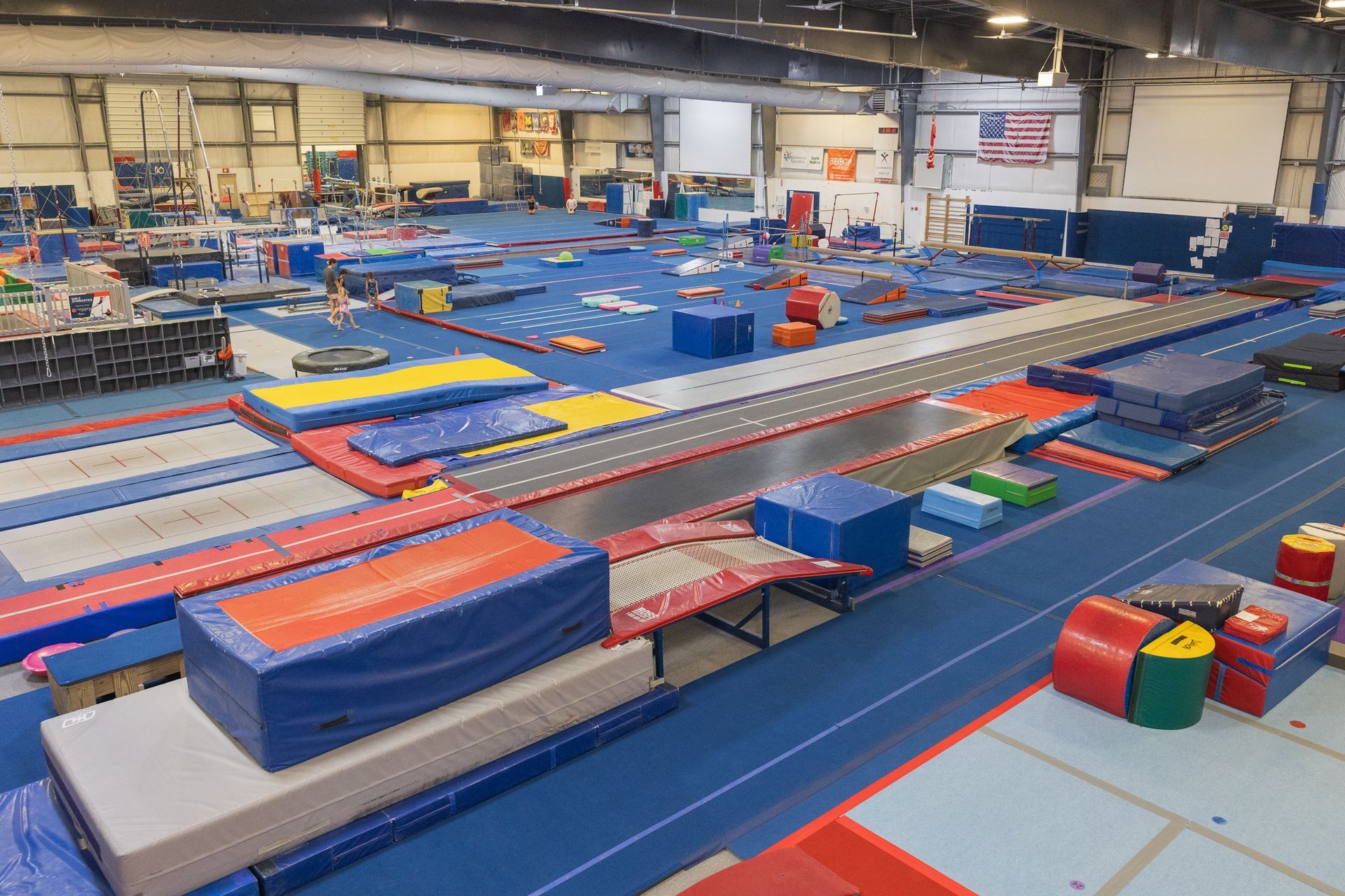 Indoor gymnastics facility with colorful foam blocks, mats, and trampolines arranged in rows
