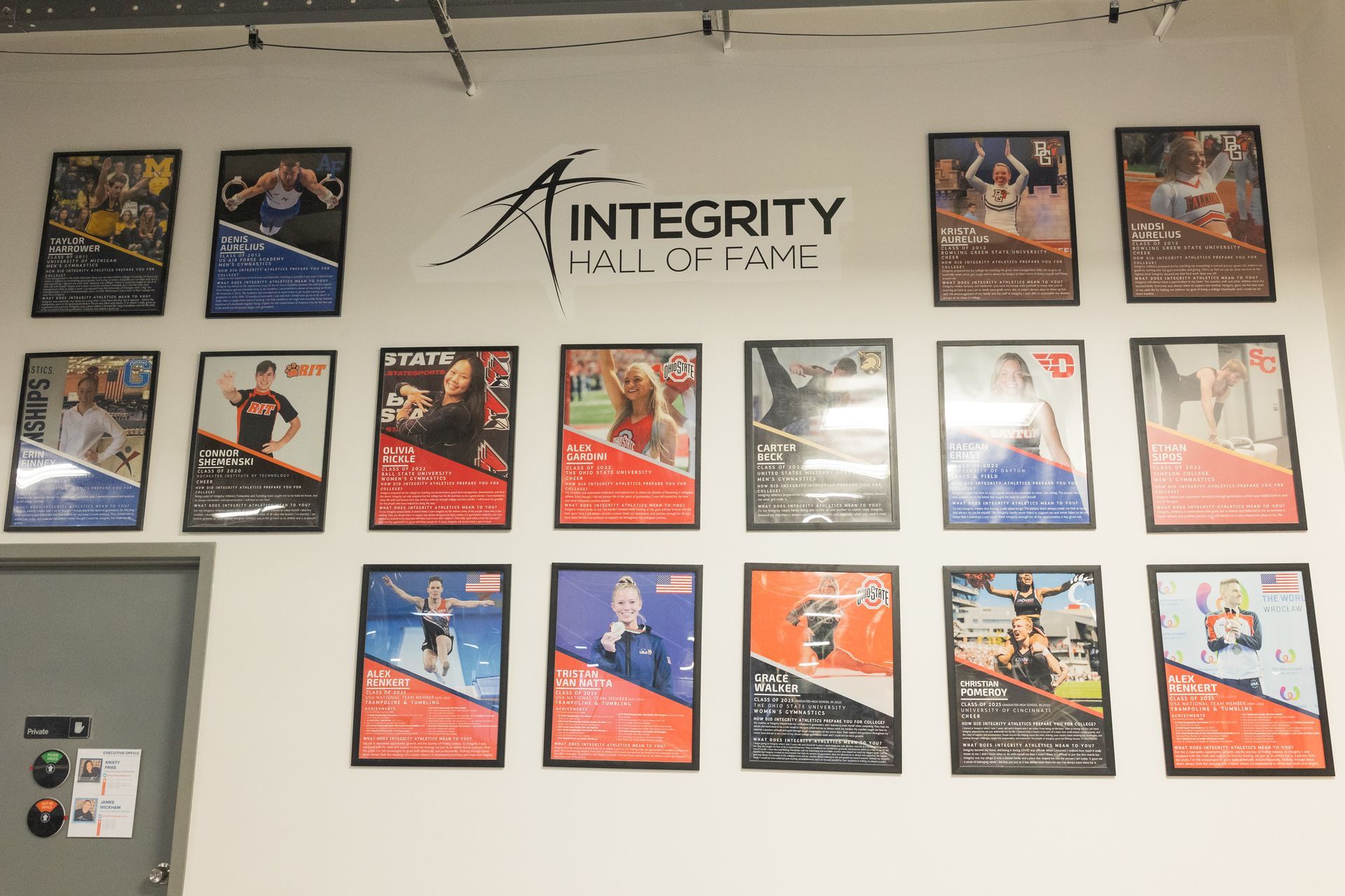 Wall display of framed posters and the “Integrity Wall of Fame” logo in a hallway or office.