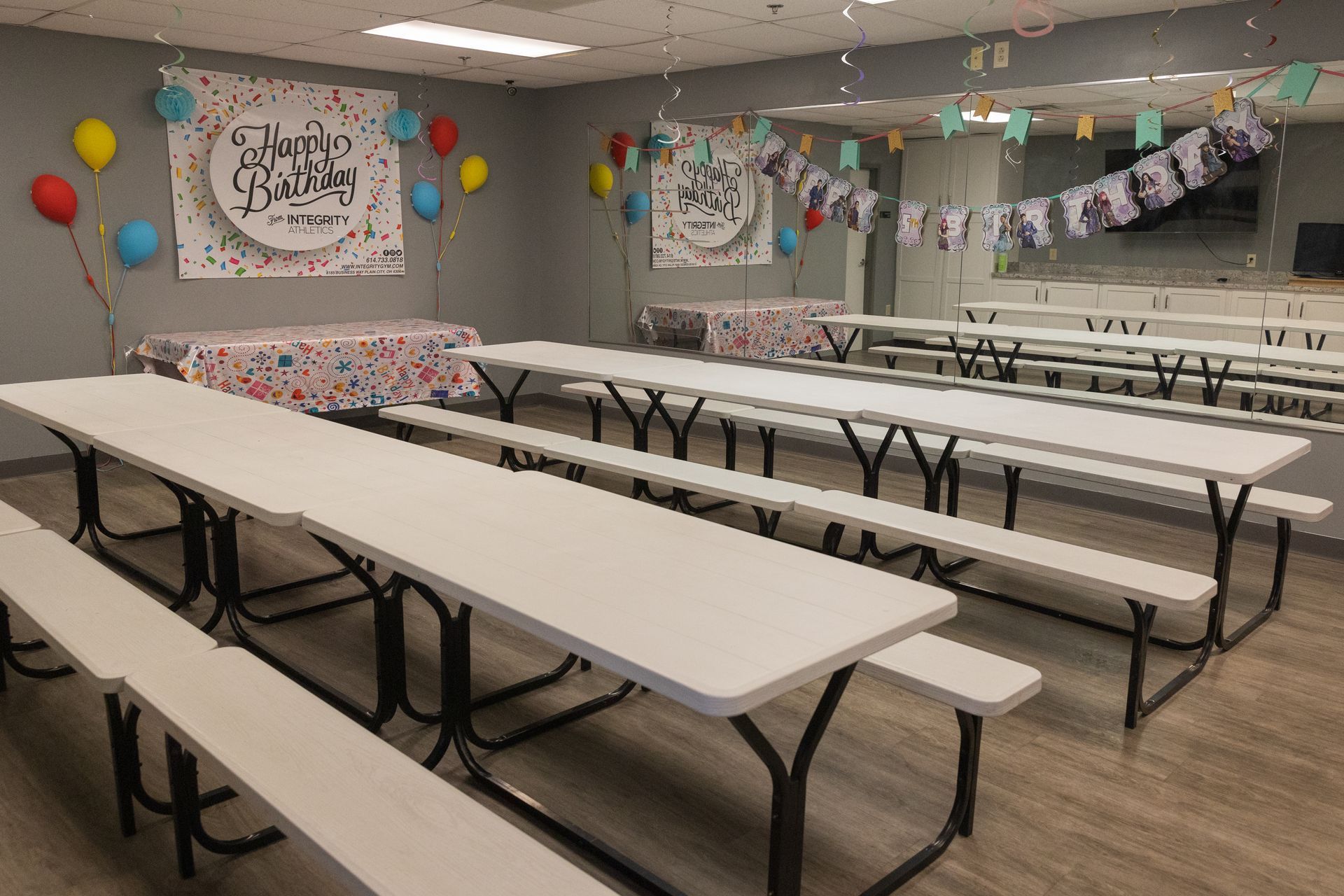 Decorated party room with long tables, balloons, and colorful banners for an event
