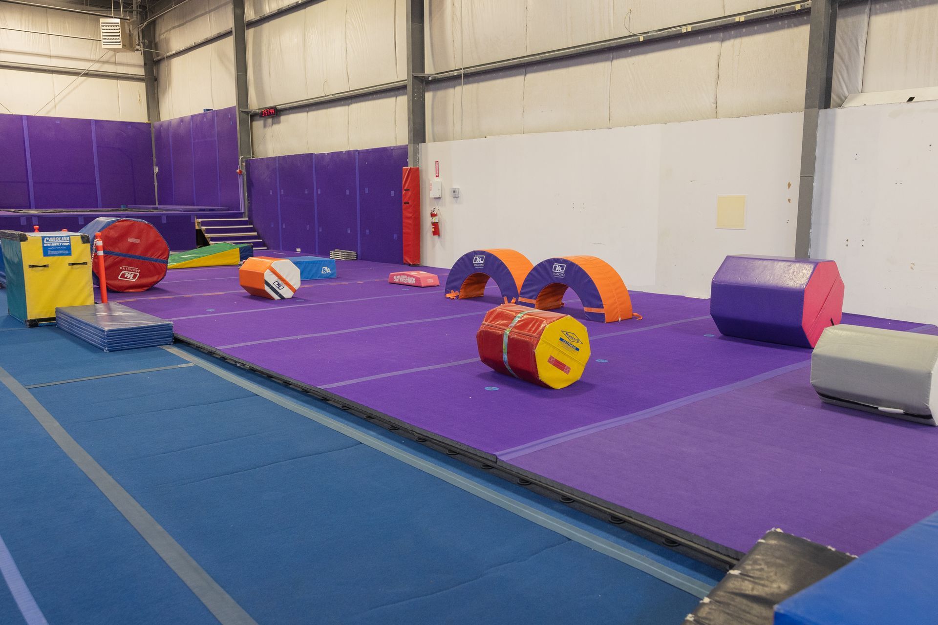 Indoor gym with purple mats and colorful foam obstacles for a gymnastics course