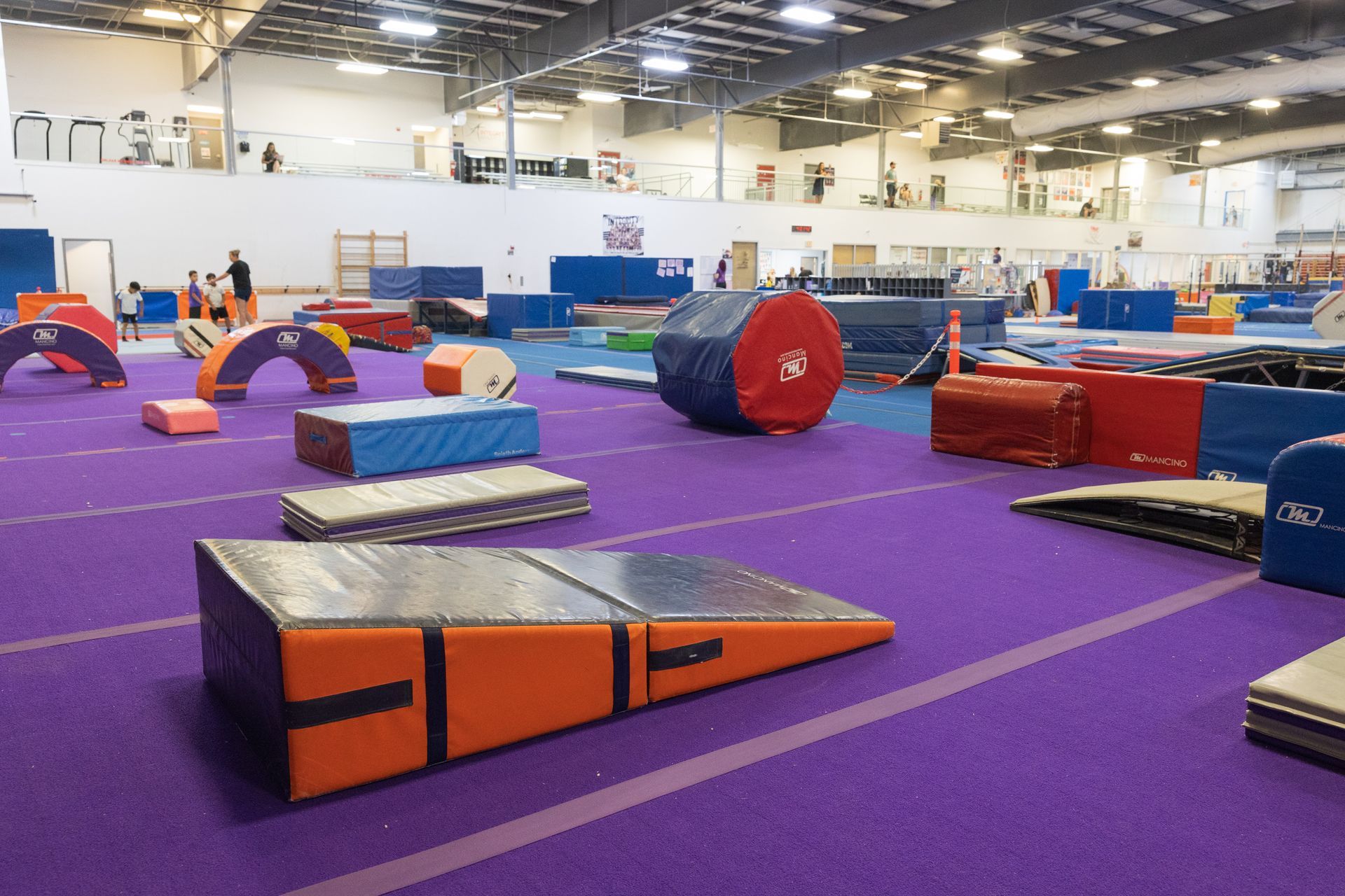 Purple indoor gym with colorful foam obstacles and mats in a large training facility
