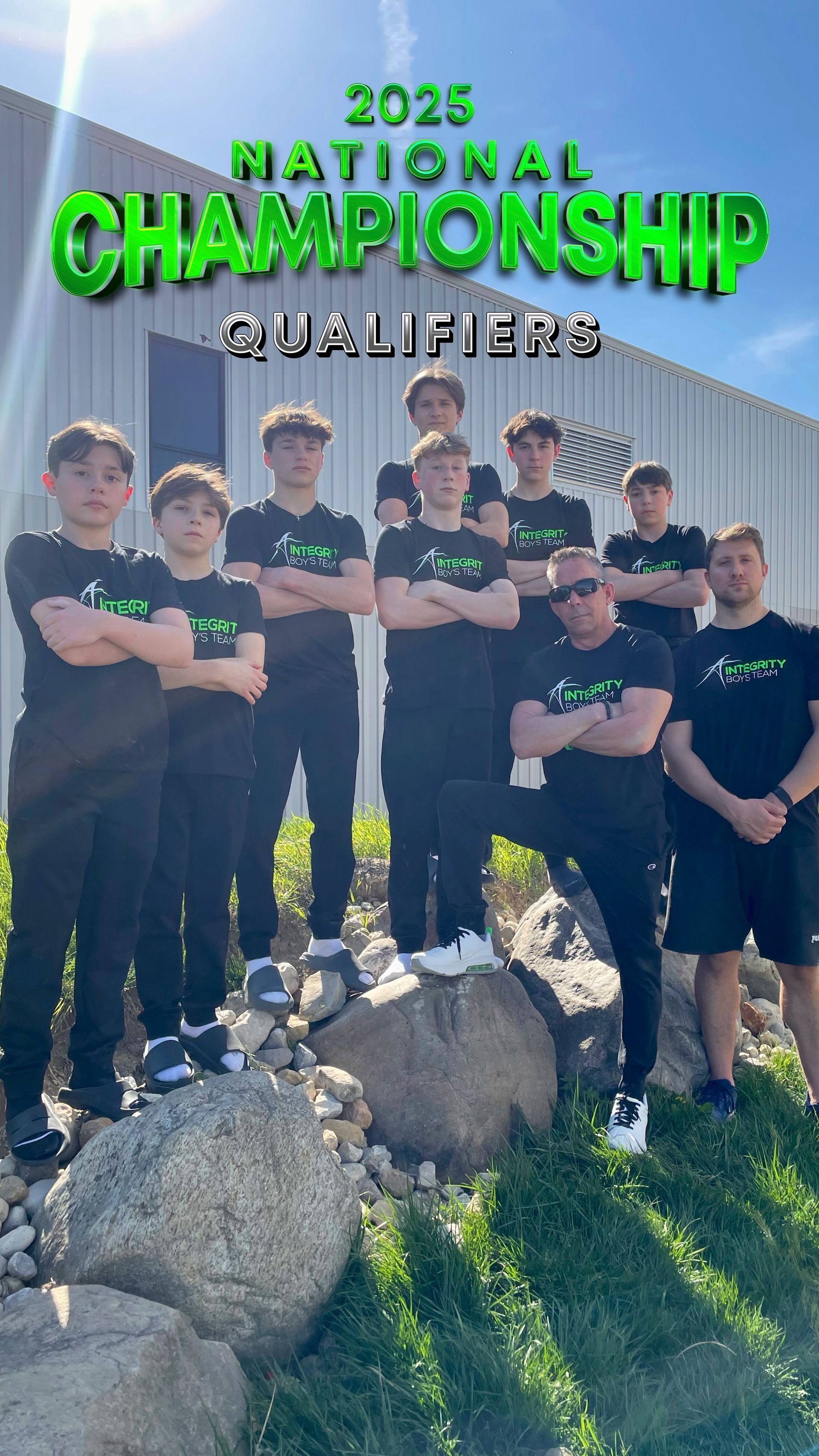 2025 National Championship Qualifiers team posing outdoors by a fence and rocks, wearing black shirts