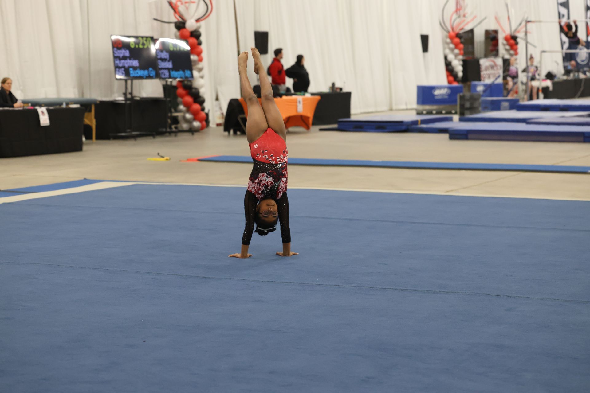 A girl is doing a handstand on a blue mat