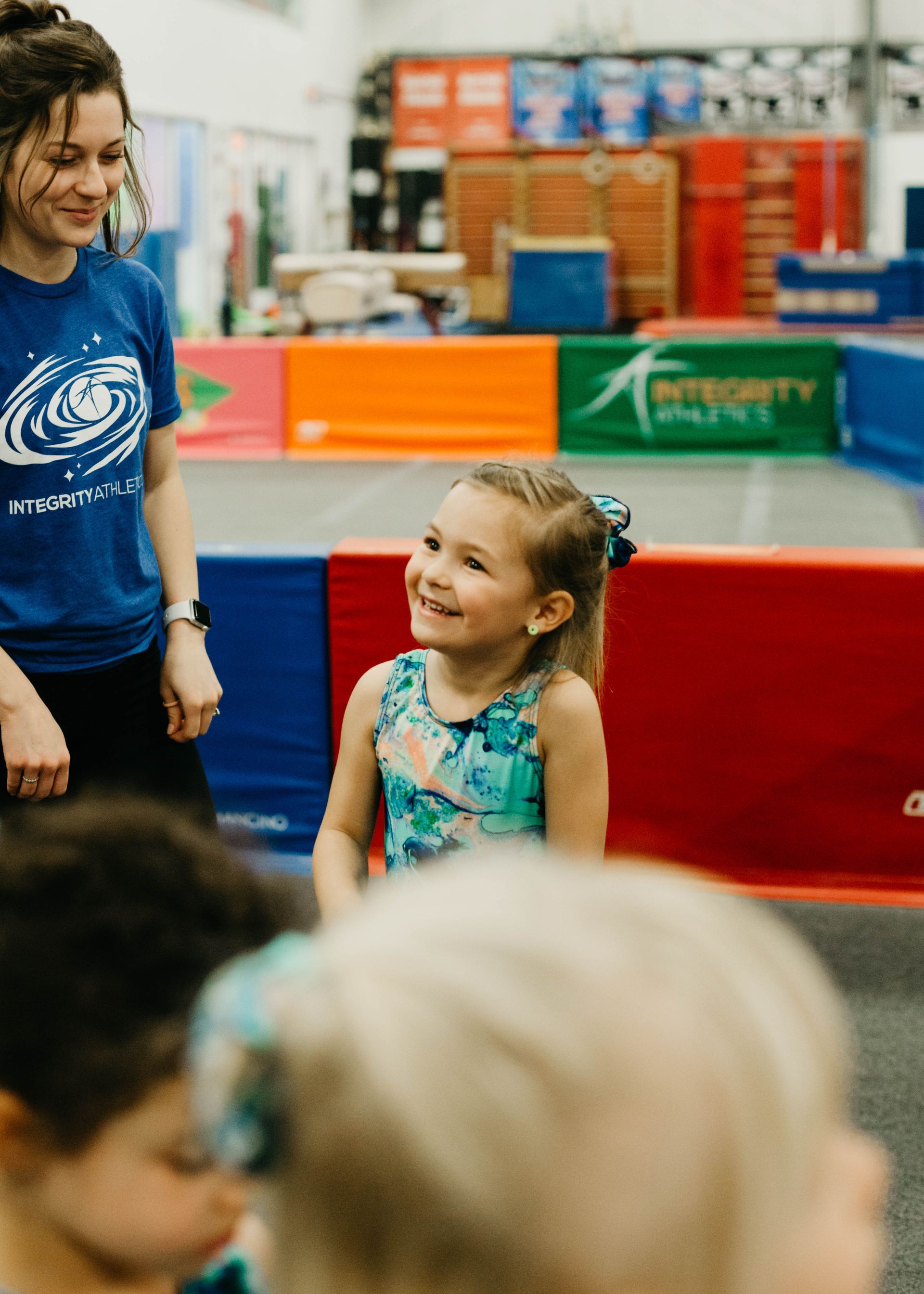 A woman is talking to a little girl in a gym.