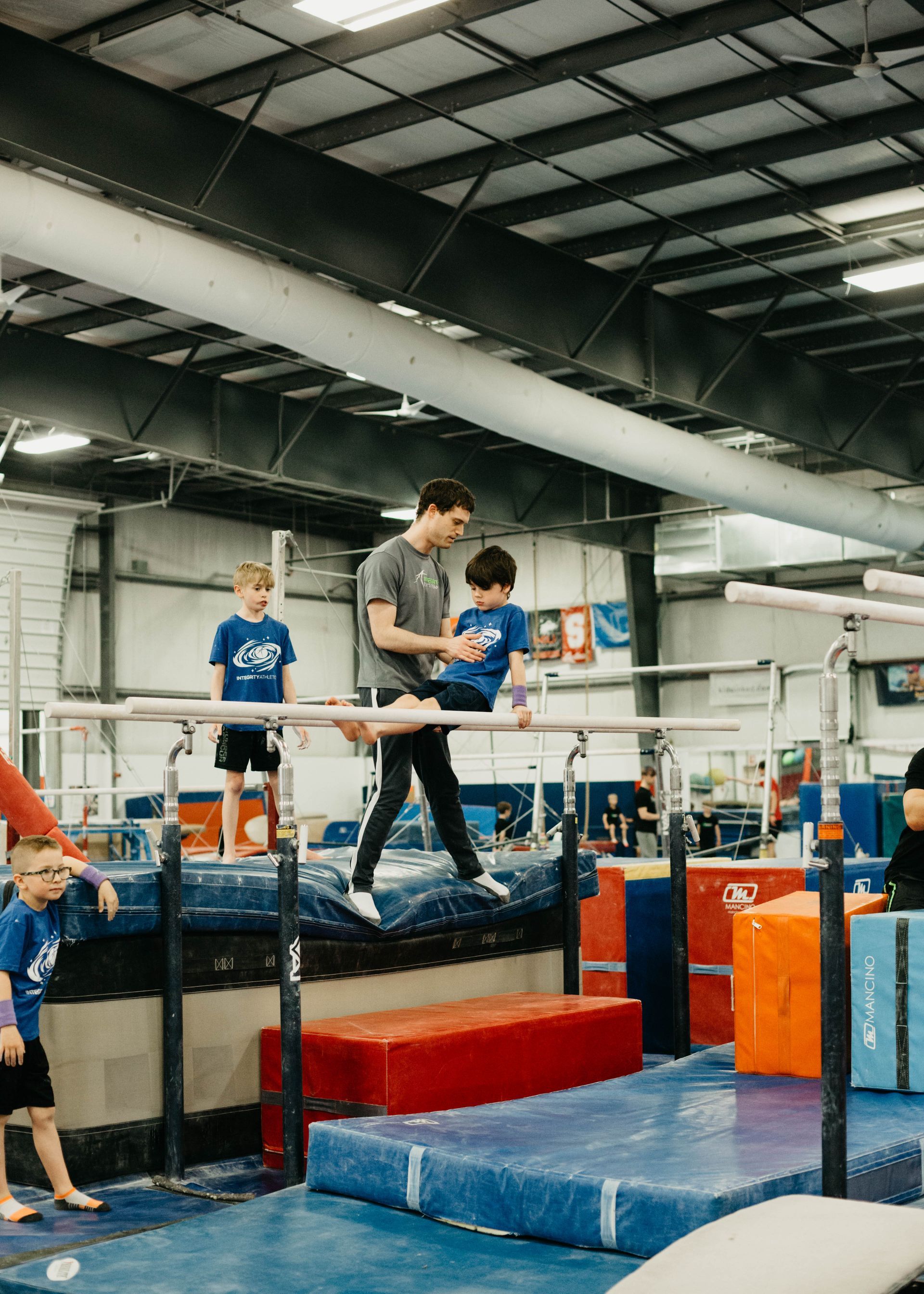 Adult and child on a trampoline in an indoor gym, with blue and red mats around them