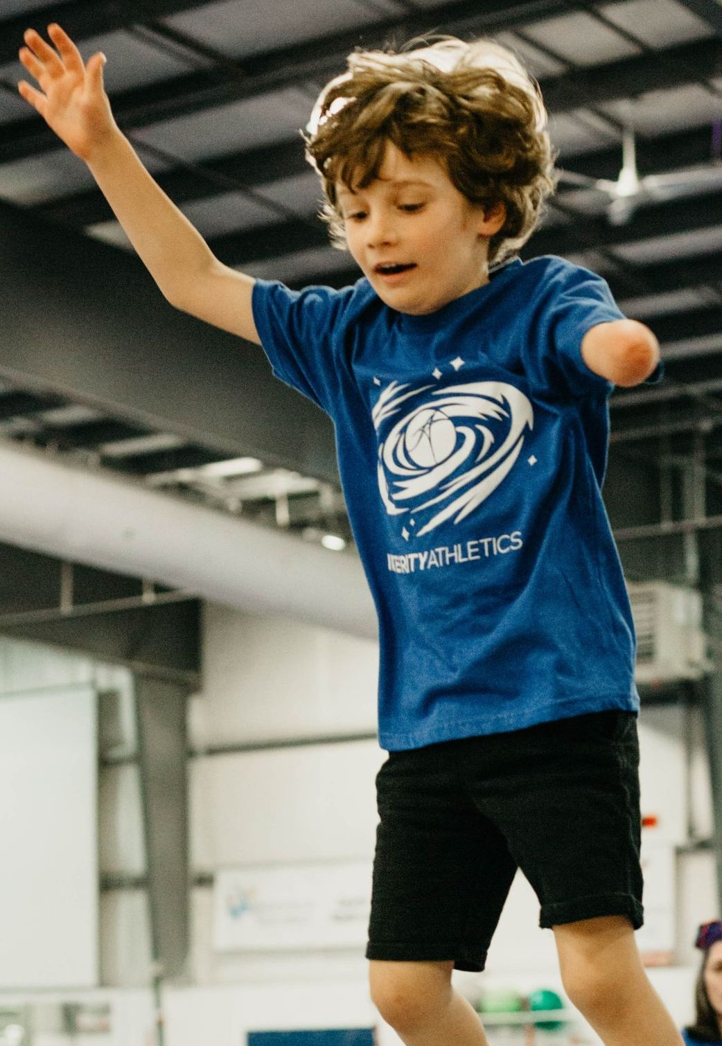 A child is standing on a balance beam in a gym.