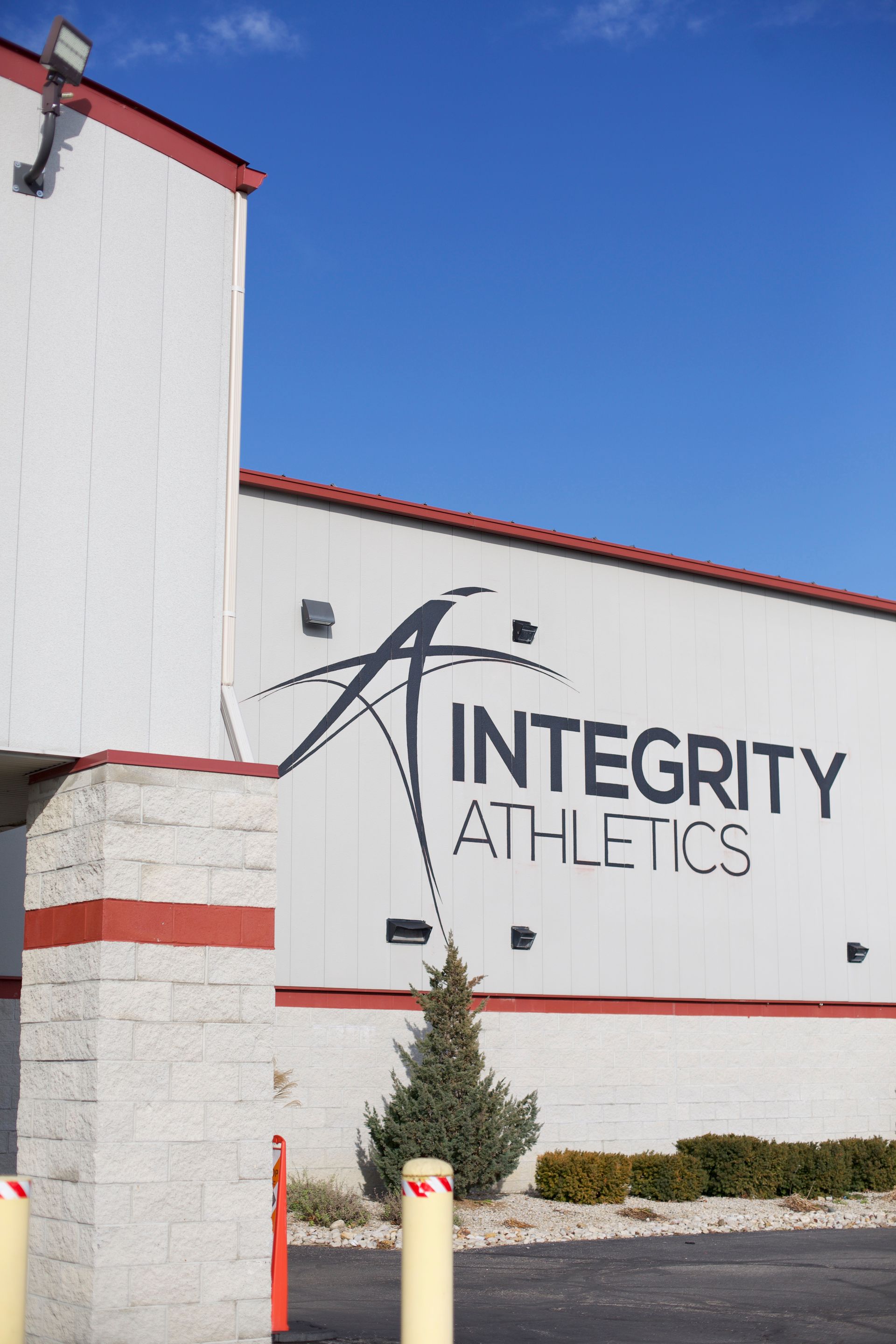 Integrity Athletics building exterior with white walls, red trim, and blue sky