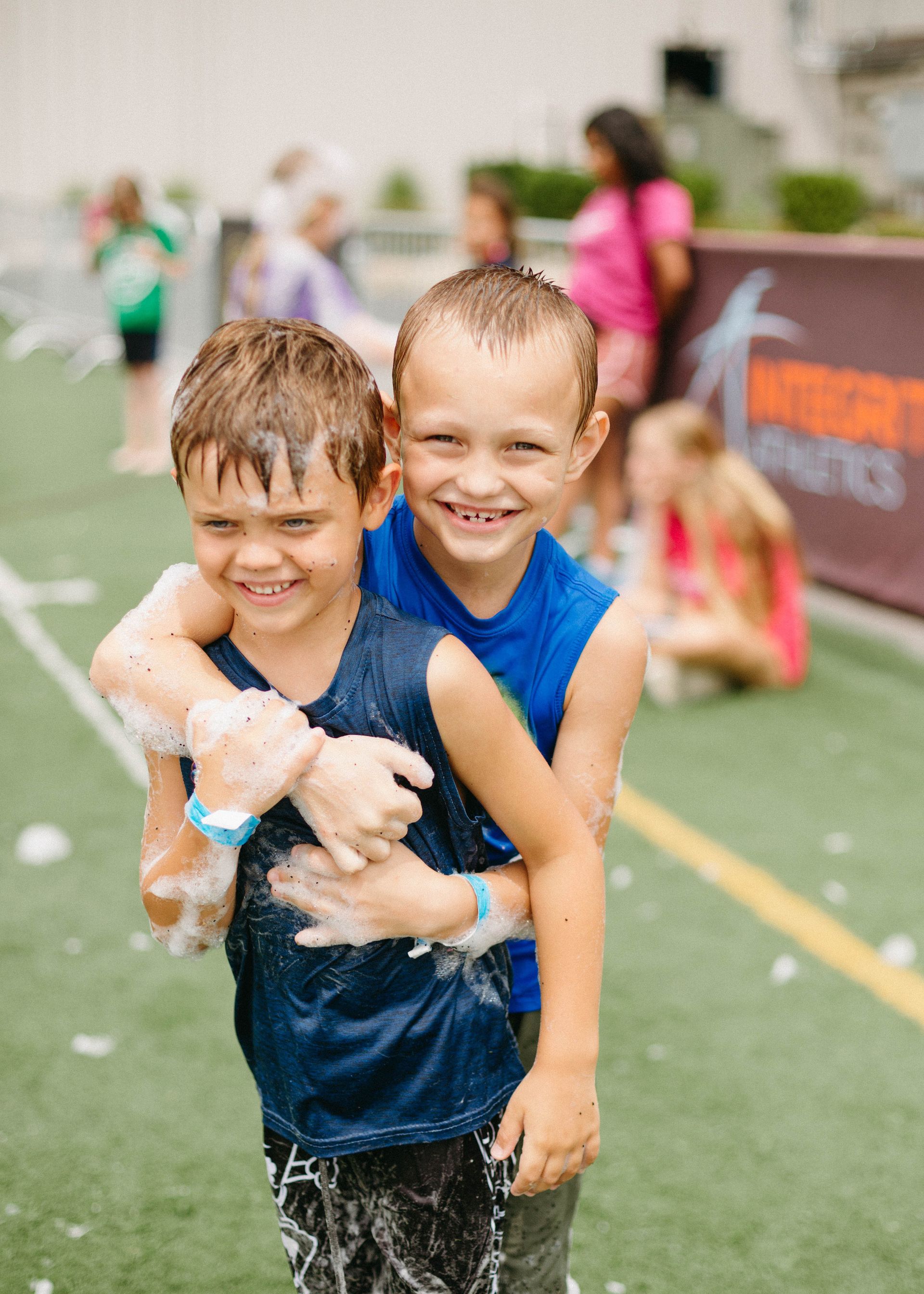 Two children smiling on a field.