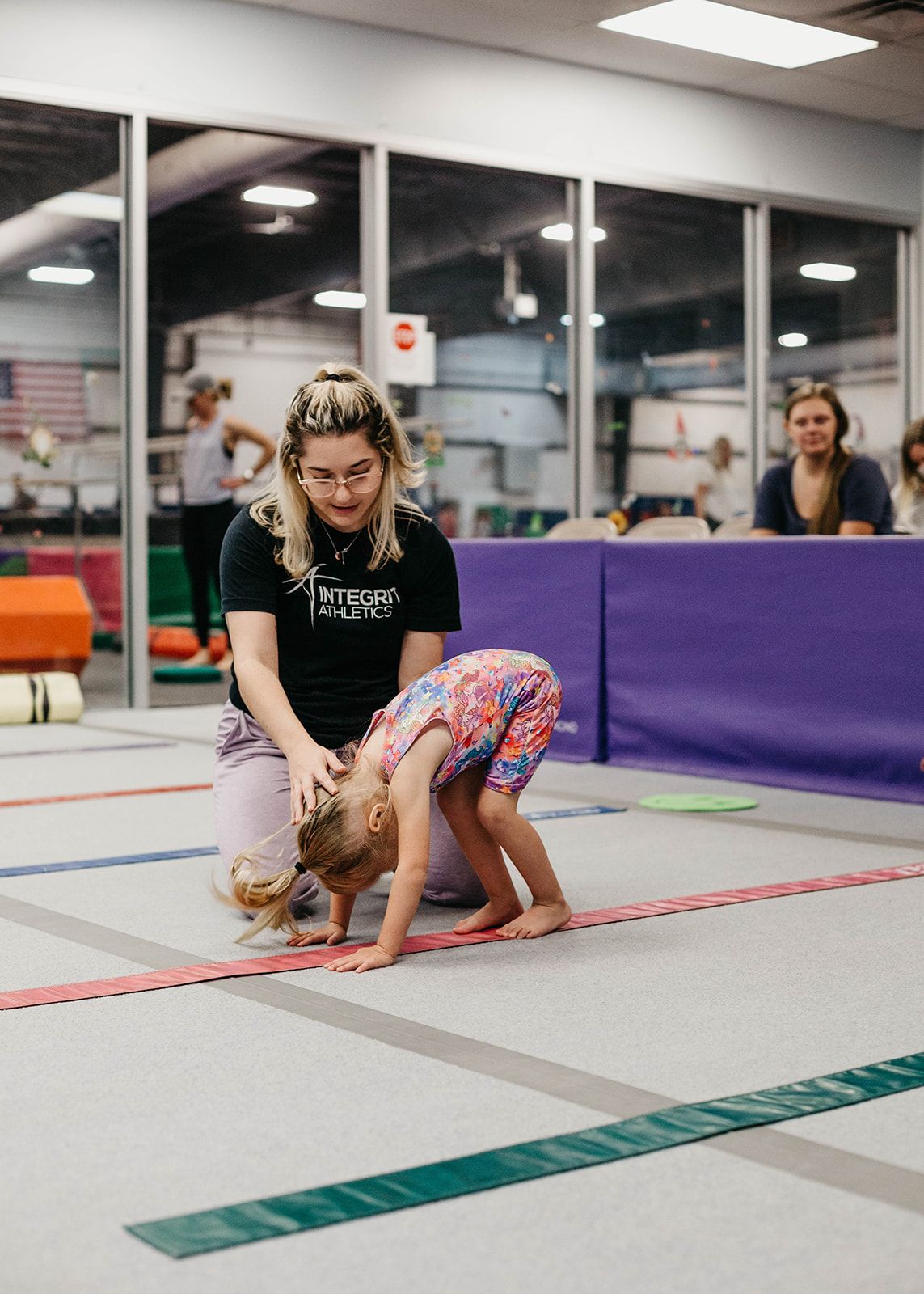 A group of young girls are practicing rhythmic gymnastics in a gym.