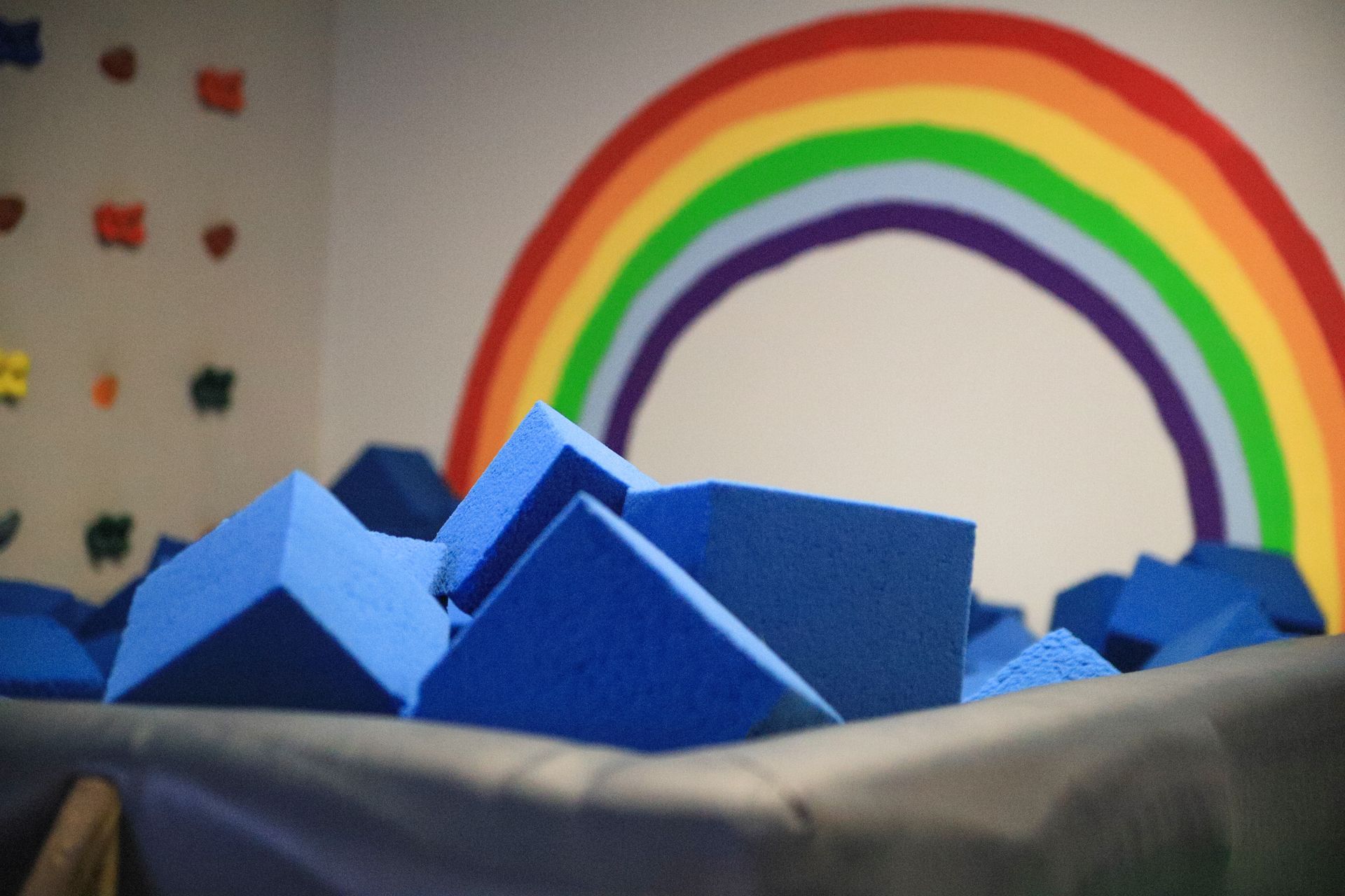 Blue foam blocks in front of a rainbow mural on a wall