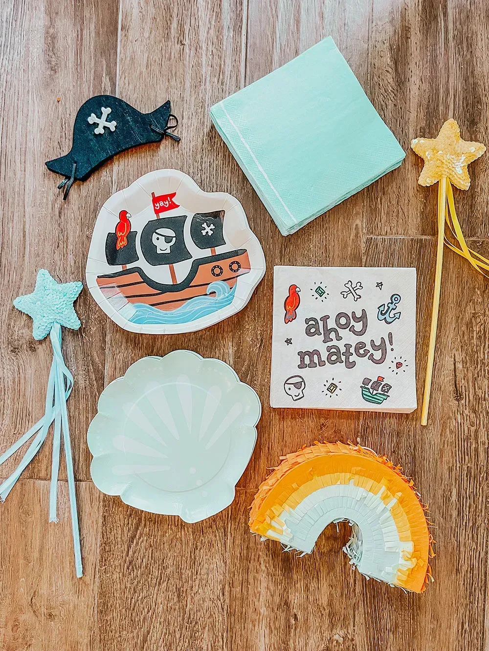 Assorted colorful pirate-themed craft decorations arranged on a wooden surface, including a ship, stars, rainbow, and note card
