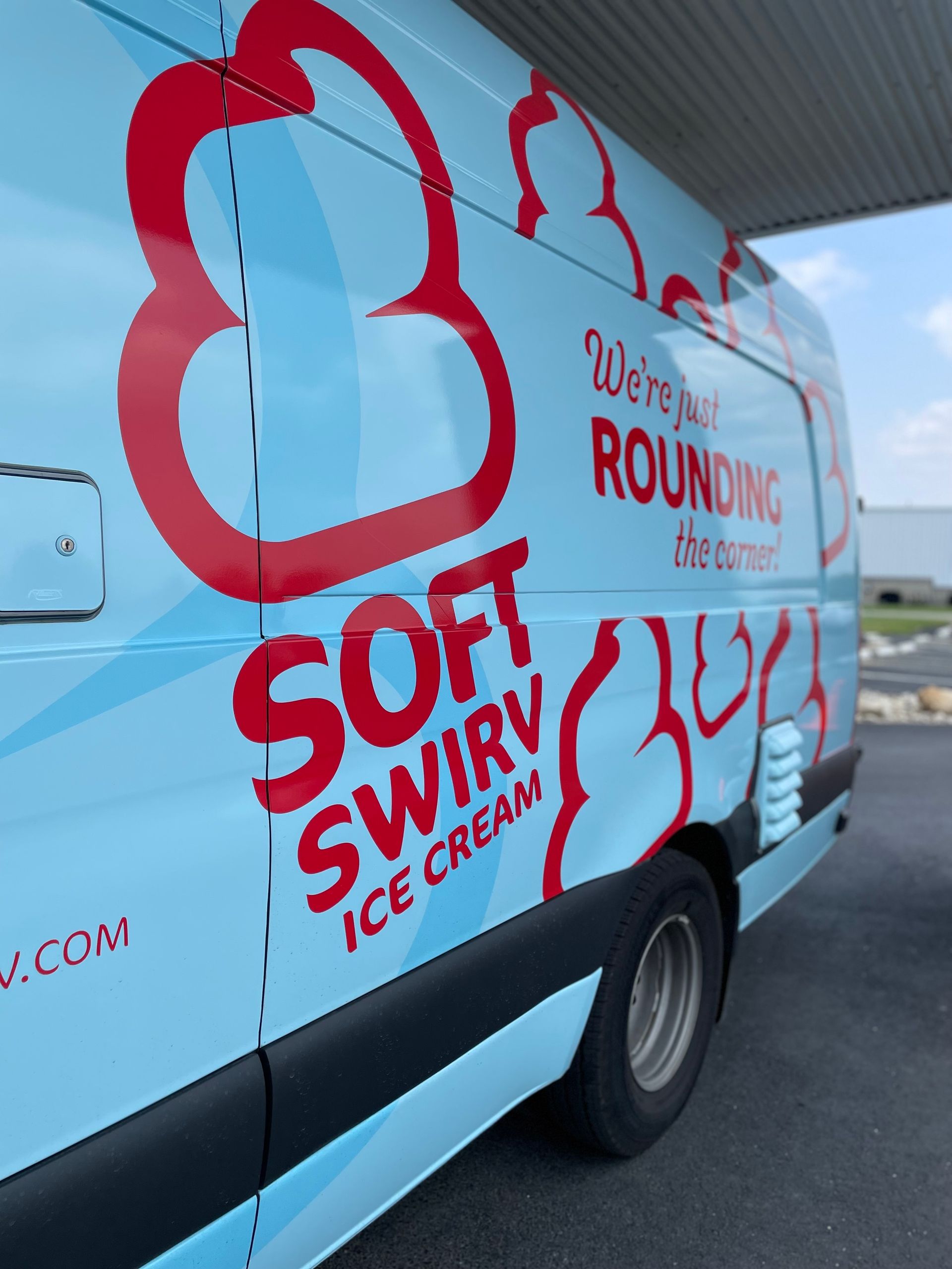 Branded ice cream delivery van with red logo and “Soft Swirl” lettering on a light blue background