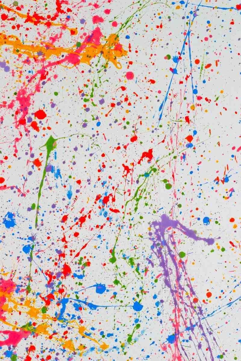 Abstract splatter painting with bright pink, orange, blue, green, and purple paint on a white background