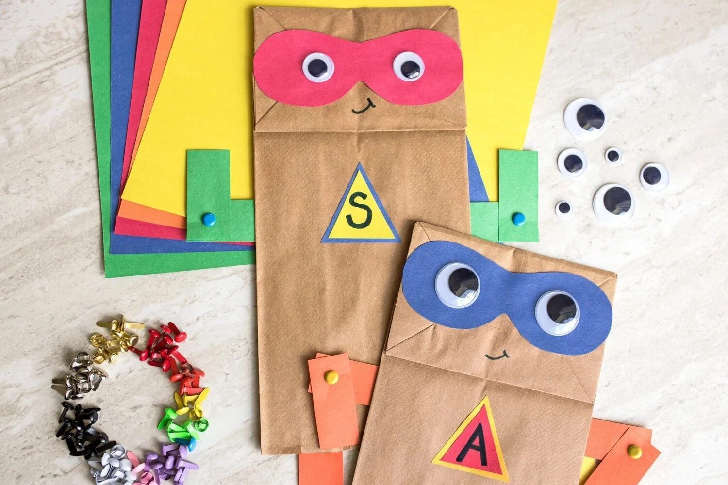 Colorful paper owls and craft supplies on a table, with googly eyes and decorated bags.