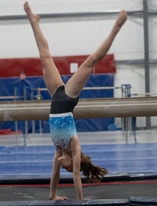 A young girl is laying on her back on a gymnastics mat.