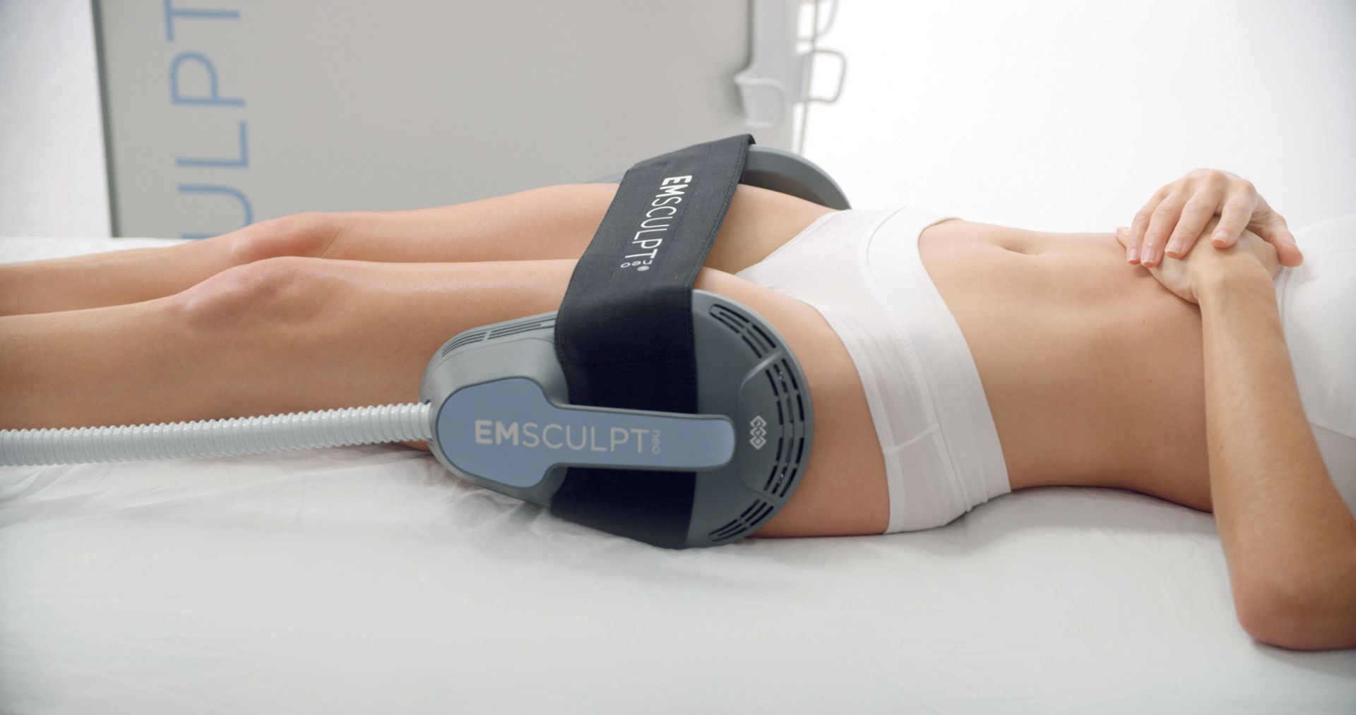 A woman is laying on a bed with a machine on her stomach.