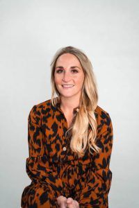 A woman in a leopard print dress is smiling for the camera.