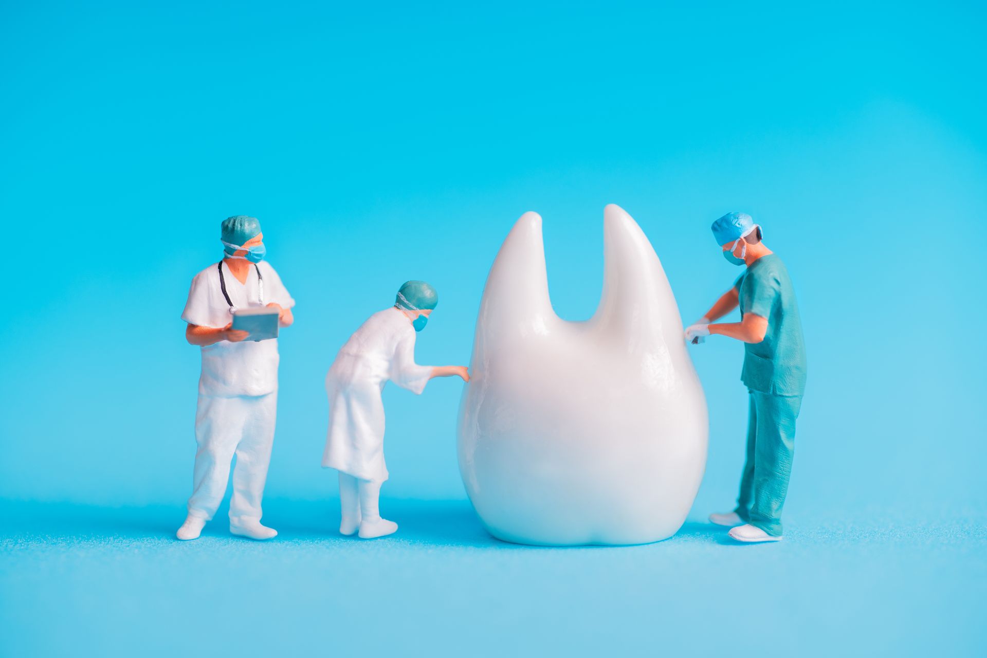 A group of dentists are working on a large tooth on a blue background.
