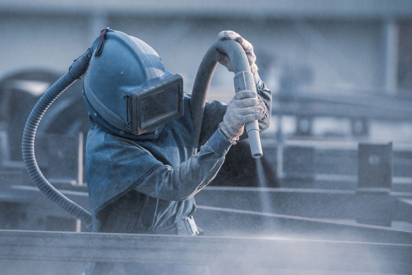 Sandblasting a piece of metal