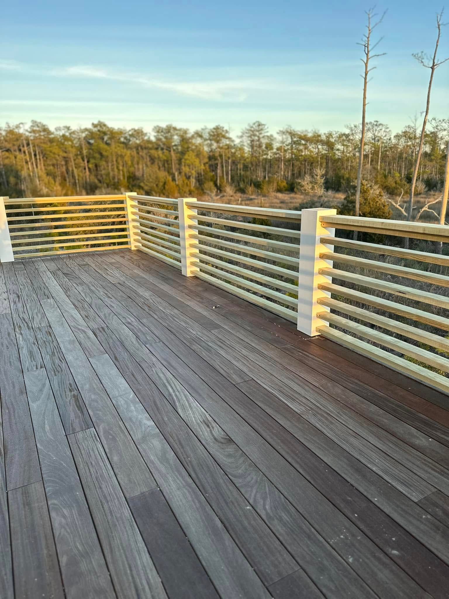 A wooden deck with a railing and trees in the background.