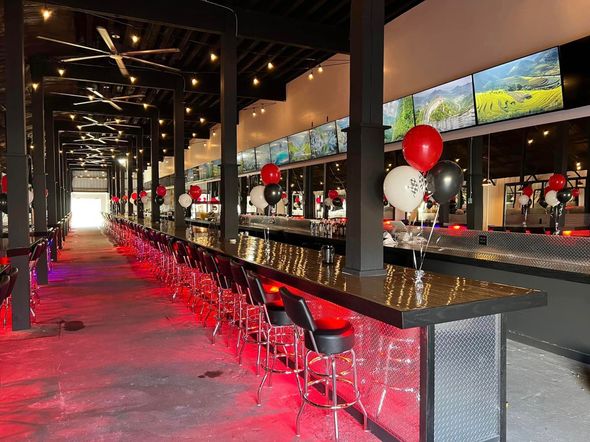 A long bar in a restaurant with red and white balloons on it.