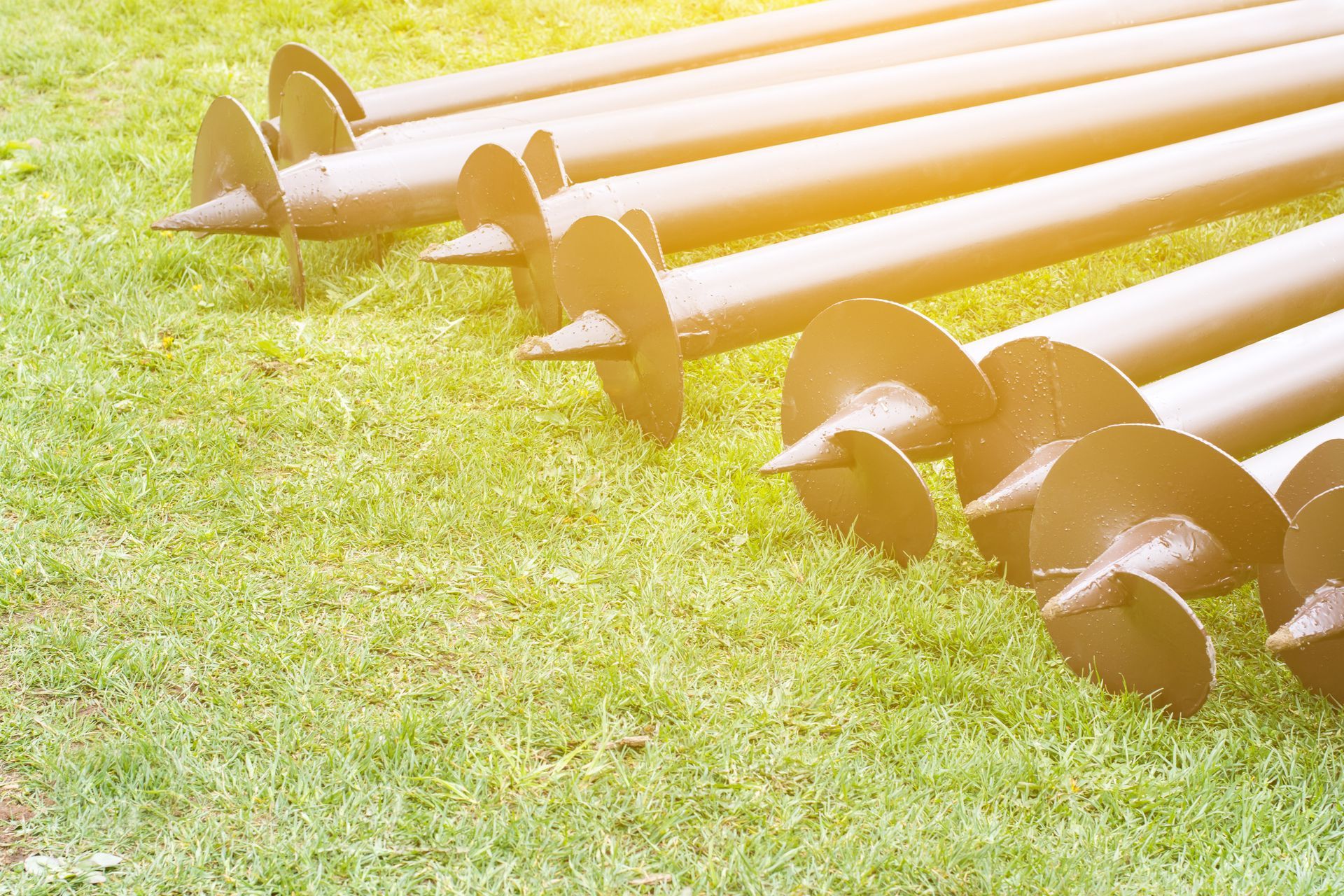 Row Of White Metal Tent Stakes With Auger Anchors Laid on Grass — Ground Screws SEQ Pty Ltd In Meridan Plains, QLD