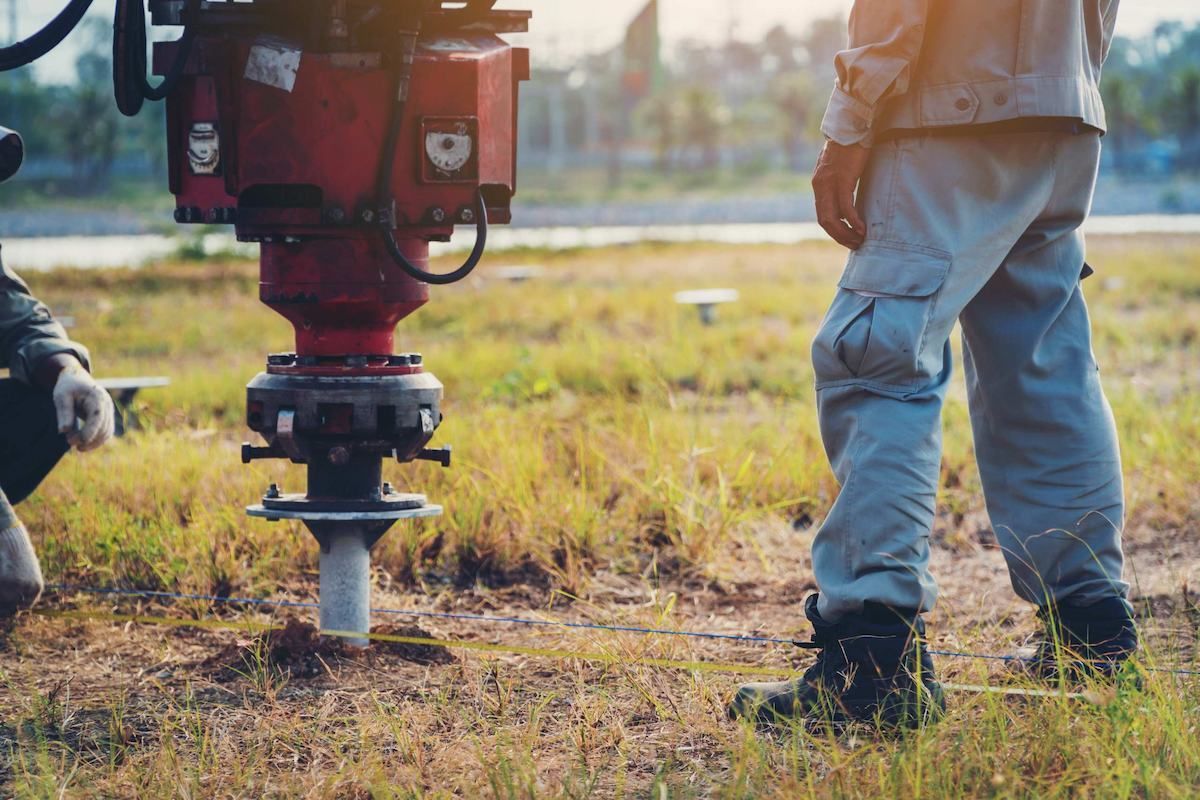 Worker Operating Red Post Driver To Install Fence Posts In A Grassy Field — Ground Screws SEQ Pty Ltd In Meridan Plains, QLD