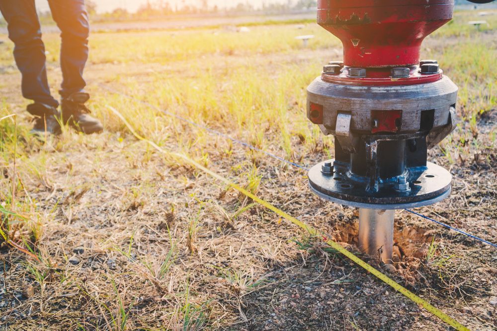 Surveying Equipment in a Grassy Field With a Person Standing Nearby — Ground Screws SEQ Pty Ltd In Meridan Plains, QLD