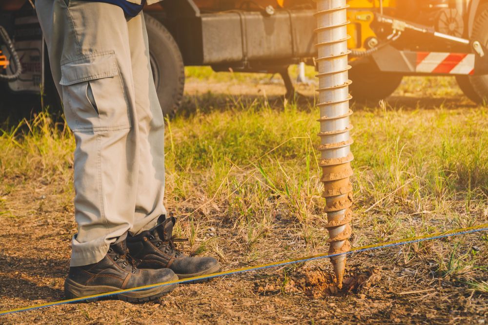 Worker Standing Beside a Drilling Auger on Dry Ground Near a Truck — Ground Screws SEQ Pty Ltd In Meridan Plains, QLD