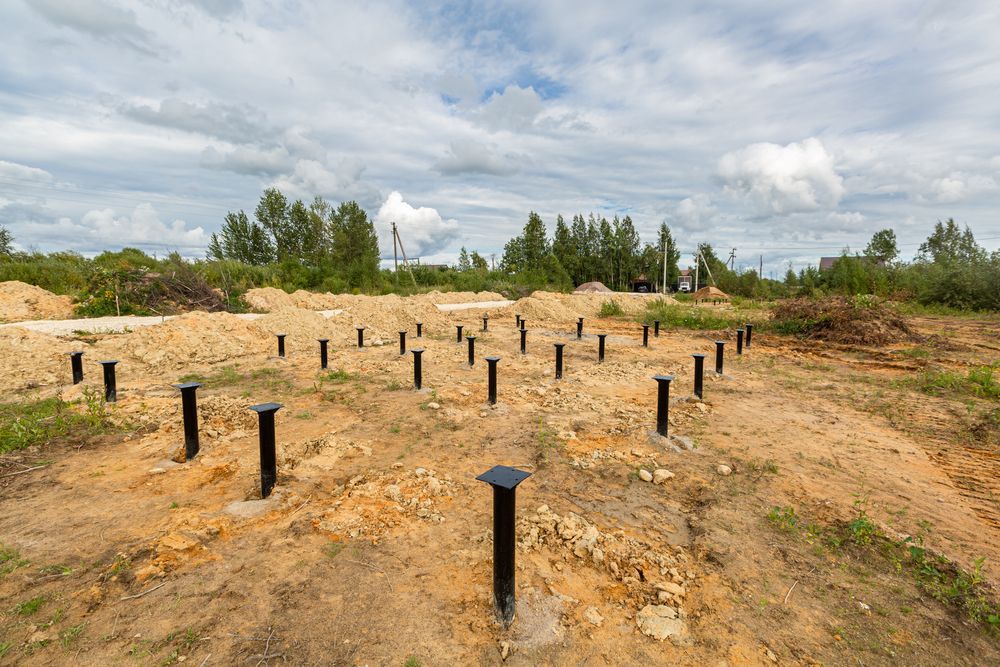 Ground With Rows of Black Metal Posts in a Sandy Clearing — Ground Screws SEQ Pty Ltd In Meridan Plains, QLD