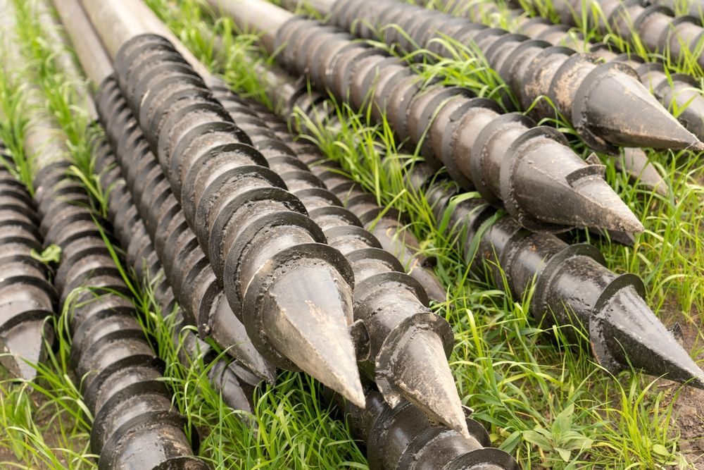 Rows Of Black Metal Auger Bits With Silver Tips Lying on Grass — Ground Screws SEQ Pty Ltd In Meridan Plains, QLD