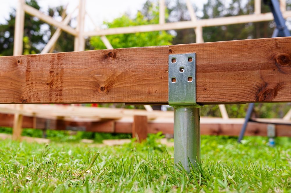 Wooden Beam on a Metal Post Above Green Grass in a Construction — Ground Screws SEQ Pty Ltd In Gladstone, QLD