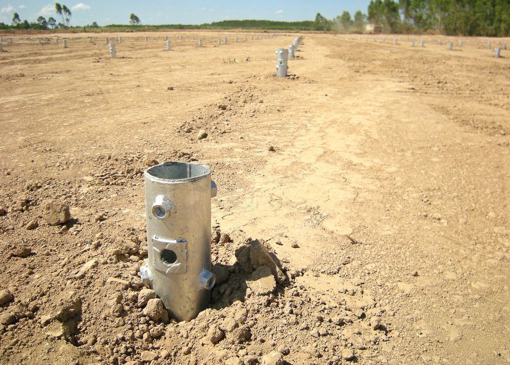 Metal Posts in a Dry Dirt Field, Lined Into the Distance Under a Clear Sky — Ground Screws SEQ Pty Ltd In Meridan Plains, QLD