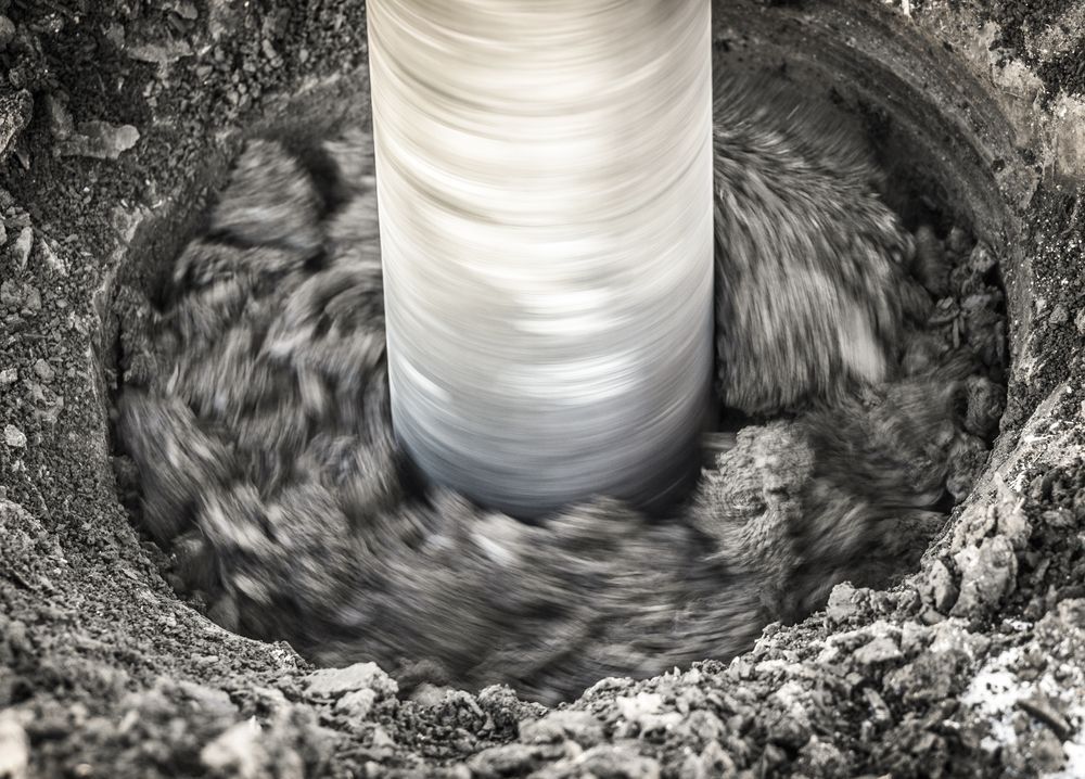 Concrete Being Mixed Around a Vertical Metal Chute in a Construction Site — Ground Screws SEQ Pty Ltd In Meridan Plains, QLD