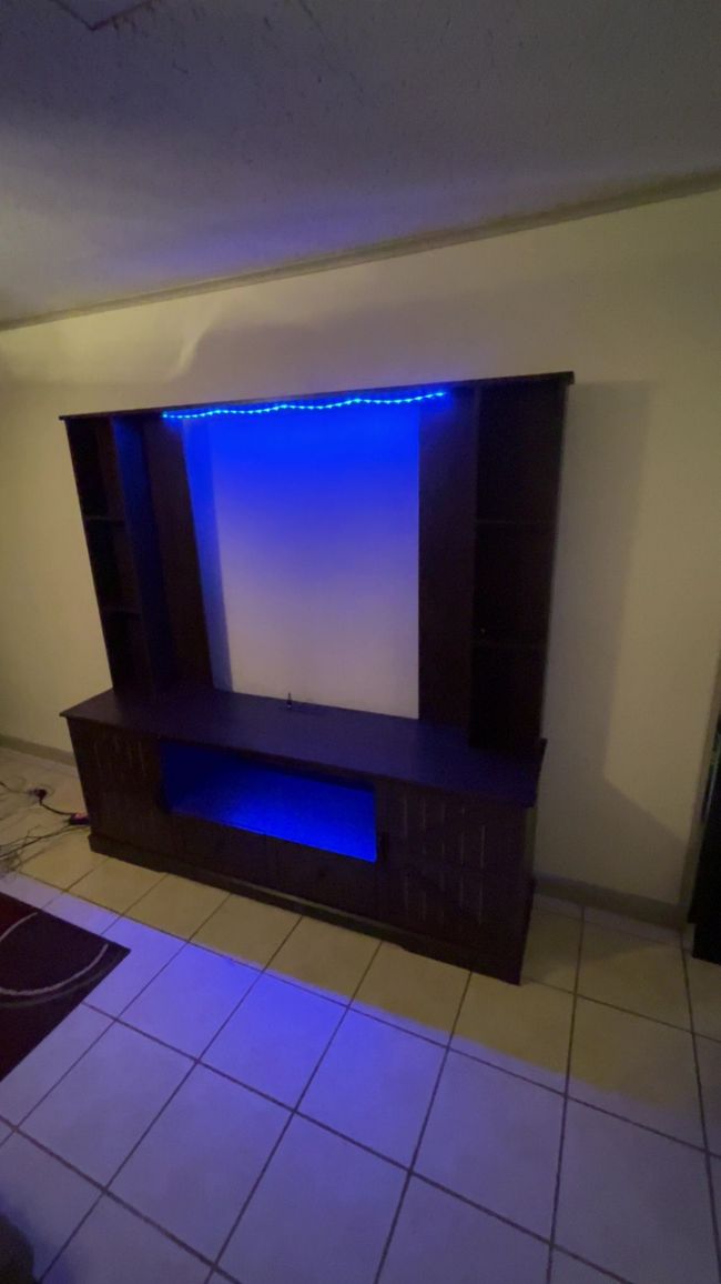 Modern wooden entertainment unit with blue LED lighting in a tiled room