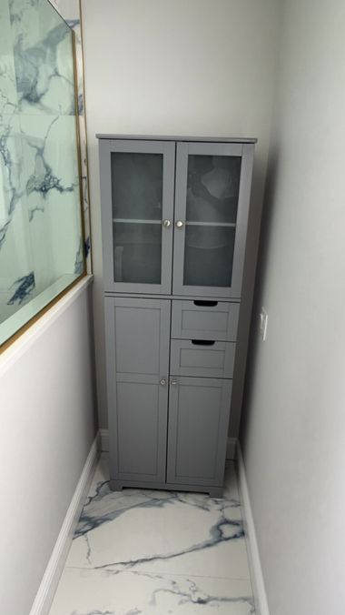 Tall gray storage cabinet in a narrow marble-tiled hallway