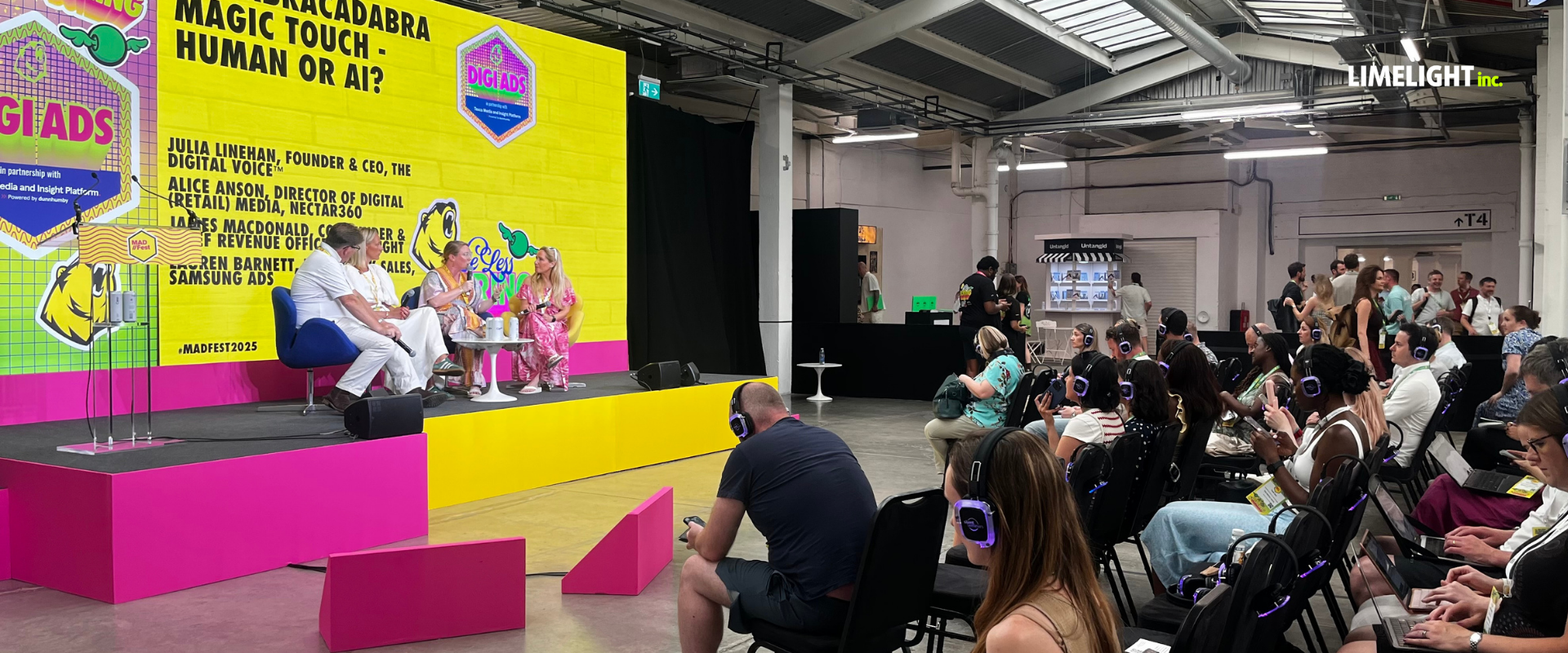 Bright yellow event stage with speakers and seated audience in a convention hall