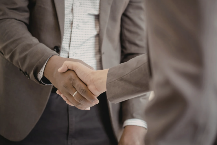 Two people in business suits shaking hands in a professional setting