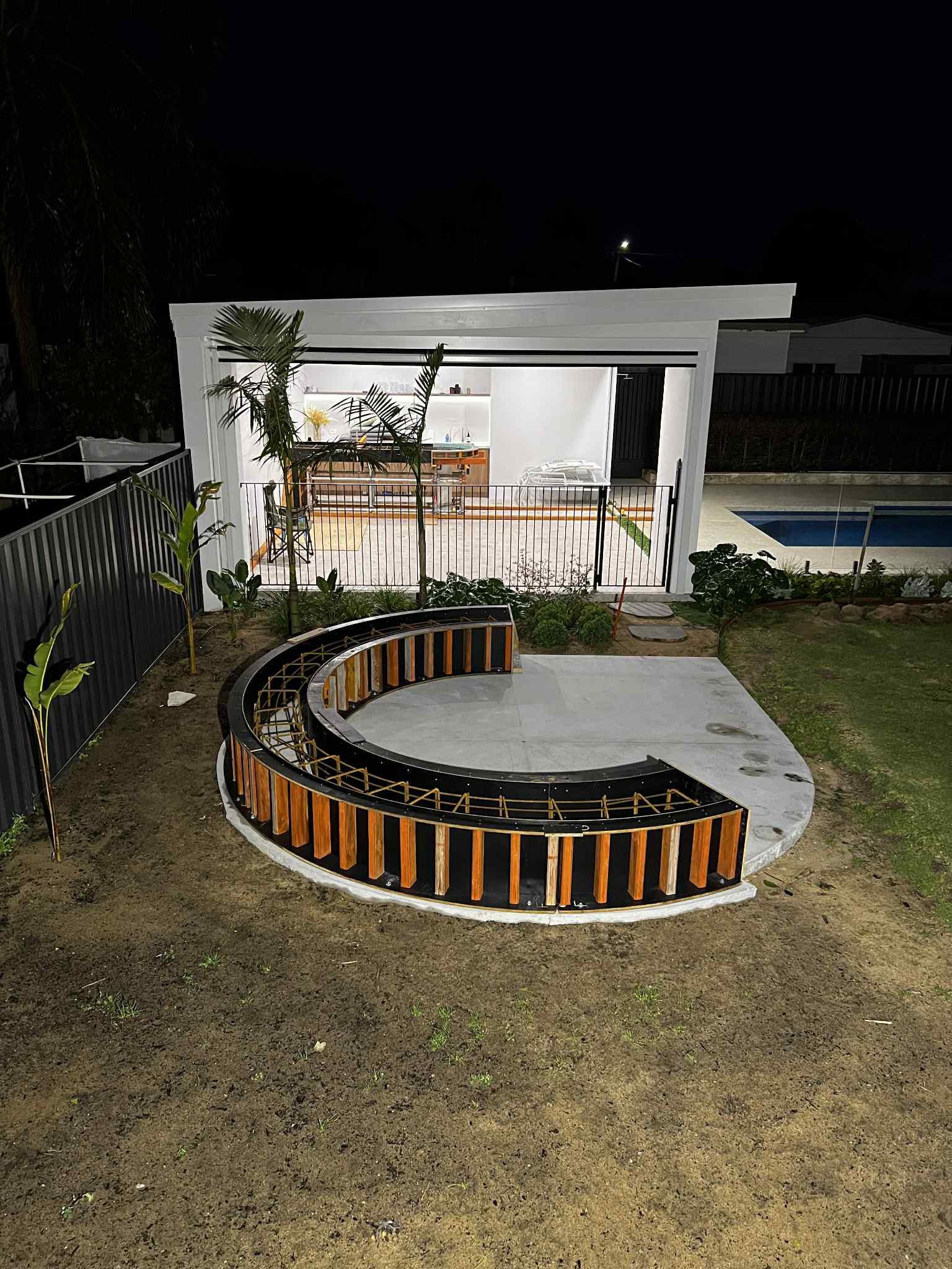Architectural concrete formwork for curved bench seat for fireplace in backyard of home.